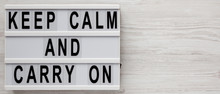 'Keep Calm And Carry On' Words On A Lightbox On A White Wooden Background, Top View. Overhead, From Above, Flat Lay. Copy Space.