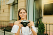 © splitov27 - Cheerful blond woman holding retro camera in the urban environment