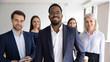 © fizkes - Group portrait of smiling motivated multiracial businesspeople stand show unity and support, happy multiethnic diverse colleagues coworkers posing together in office, teamwork, leadership concept