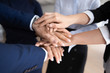 © fizkes - Close up of diverse businesspeople stack hands show unity and support in work, supportive motivated multiracial colleagues coworkers engaged in teambuilding activity at meeting, teamwork concept