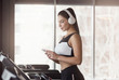 © Prostock-studio - Charming girl with smartphone and headphones listening to music on treadmill, copy space