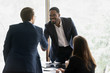 © fizkes - Smiling multiracial male business partners handshake greeting getting acquainted at office meeting, happy divers multiethnic man colleagues shake hands close deal or make agreement at briefing