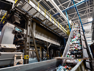 GRODNO, BELARUS - OCTOBER 2018: recycling plant conveyor belt transports garbage inside drum filter or rotating cylindrical sieve with trommel or sorting pieces of garbage into various sizes fractions