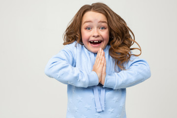 cute teenage girl in a blue hoodie prays to buy something on a light gray background