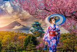 Fototapeta  - Asian woman wearing japanese traditional kimono at Osaka Castle and full cherry blossom, with Fuji mountain background, Japan.