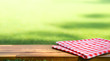© hakinmhan - Red checked tablecloth on wood with blur green courtyard background.Summer and picnic concepts