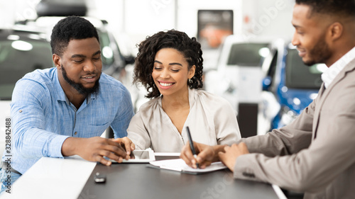 Spouses Signing Papers With Auto Seller In Dealership Office, Panorama
