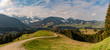 Panorama on the Hündle, a summit in the Allgäu, with a magnificent view over snow-covered mountains and green valleys and a hiking trail