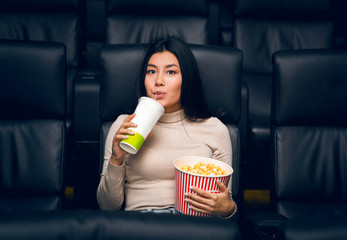 Wall Mural - Cute Asian girl with popcorn and drink in cinema