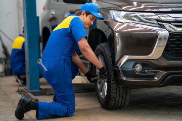 Mechanician changing car wheel in auto repair shop