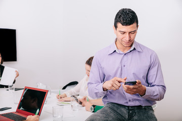 Wall Mural - A businessman using his cellphone sitting at the office table