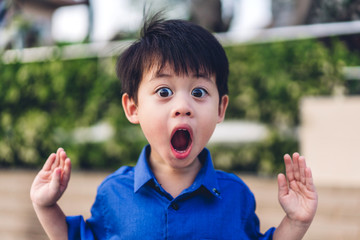 Portrait of cute little asian boy child fear and excited face.Kid felling shocked and surprise expression something outdoor