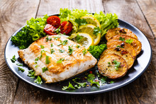 Fish Dish - Fried Cod Fillet With Potatoes And Vegetables On Wooden Table
