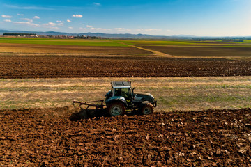 aerial view of the tractor plows in the field,