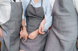 © Surachetsh - Close up to Three Asian Females chaf stand side by side to show the good relationship of friendship by wear gray apron and hold hand together.