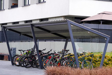 Modern Parking Lot With A Bicycle Roof Near An Apartment Building With A Large Number Of Bicycles. Eco-friendly And Sports Transport In The City.