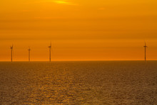 Wind Turbines In The North Sea With A Red Sky And Reflections On The Water At Sunset