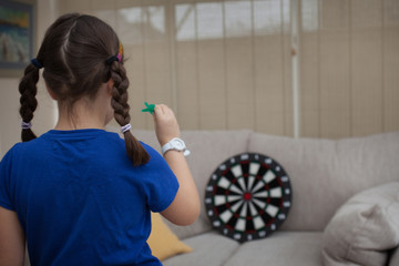 A young girl playing darts at home