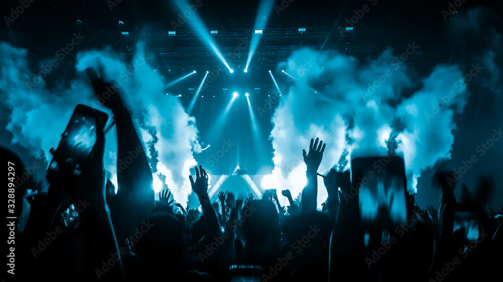Happy people dance in nightclub DJ party concert and listen to electronic dancing music from DJ on the stage. Silhouette cheerful crowd celebrate New Year party 2020. People lifestyle DJ nightlife. - obrazy, fototapety, plakaty 
