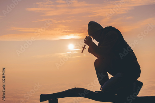 The silhouette in the hands of a man holding a wooden cross, a Christian cross and a cross background as a sunrise, concepts for Christians, Christianity, Catholicism, God, Heaven, Heaven or God.
