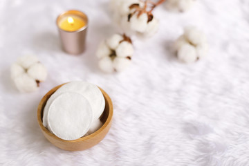 Cotton facial pads for removal makeup with natural cotton flowers and candle on white fur background, hygiene and healthy care lifestyle