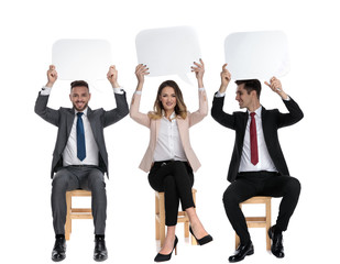 Canvas Print - Three positive businessmen holding speech bubble above their heads