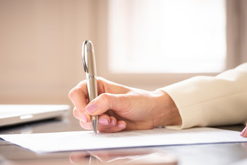 Businesswoman's hand while writing something with pen