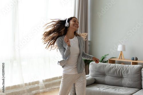 Cuadros en Lienzo Overjoyed millennial girl wearing headphones have fun moving listening to music