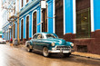 old blue green classic car in front of blue building in havana cuba