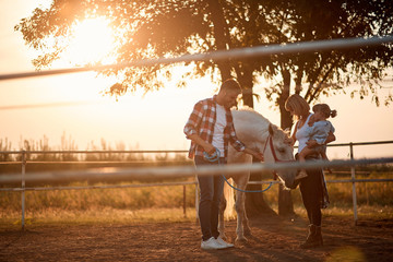  Girl and family with a horse in the farm. Petting horses in countryside.