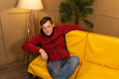 © Anton Dios - A confident, happy young man is resting on the couch at home. A visiting man in casual clothes while sitting on a yellow sofa at home