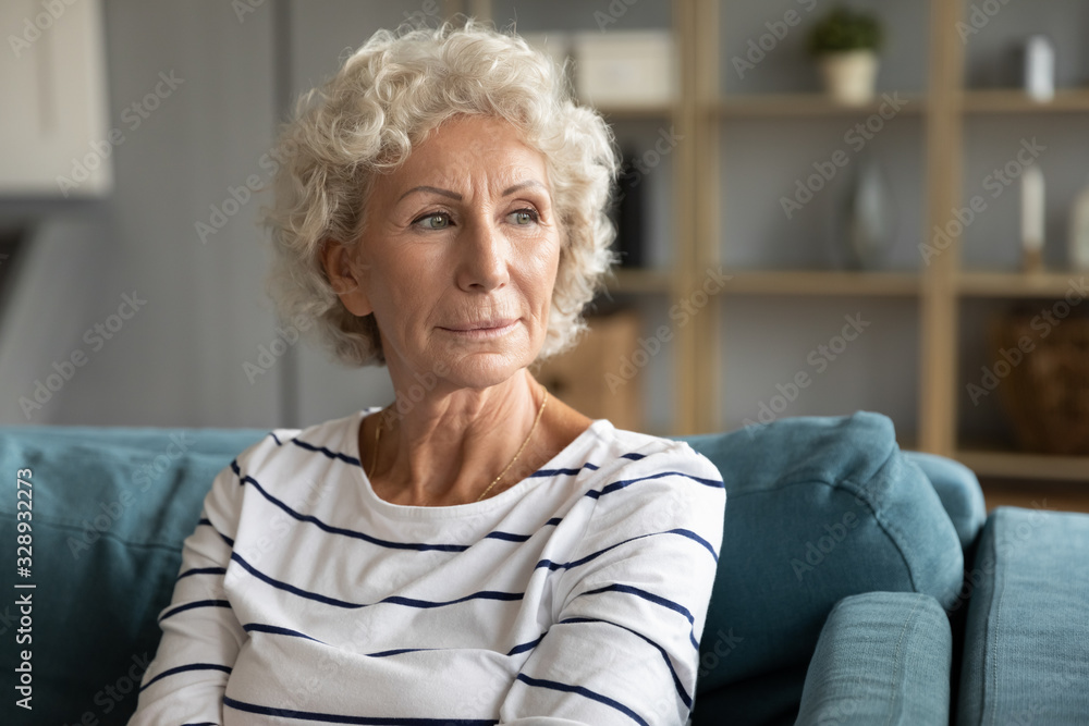 Pensive old middle-aged 60s woman look in distance thinking pondering, thoughtful elderly lady sit relax on couch in living room daydreaming or visualizing, lost in thoughts missing mourning - obrazy, fototapety, plakaty 