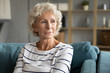 © fizkes - Pensive old middle-aged 60s woman look in distance thinking pondering, thoughtful elderly lady sit relax on couch in living room daydreaming or visualizing, lost in thoughts missing mourning