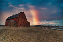 Stunning Dramatic Sunsets In Rural Farm Country With Barns And Cold Fields With Rainbow.
