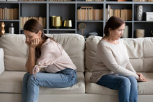 Stressed Young Woman Sitting Separately With Offended Mature Old Mother In Living Room. Unhappy Grownup Daughter And Stubborn Senior Mommy Ignoring Each Other After Quarrel, Different Generations Gap.
