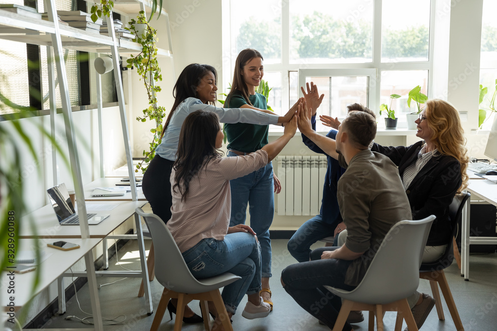 Excited multiracial colleagues give high five celebrate company ...