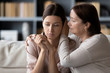 © fizkes - Compassionate middle aged mother comforting stressed upset daughter, sitting together on sofa at home. Kind senior mature mommy supporting soothing frustrated desperate unhappy grownup child.