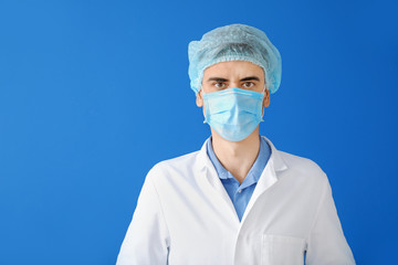 Wall Mural - Male doctor with protective mask on color background. Concept of epidemic