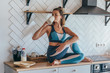 © undrey - Athletic woman having breakfast in the kitchen, girl sitting on table and drinking