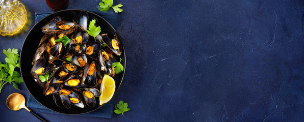 A plate with steamed mussels on dark blue background