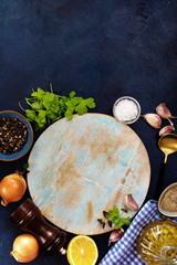 Wall Mural - Flat lay of round cutting board and cooking ingredients on blue background