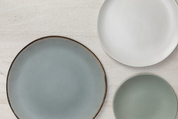 Group of empty blank ceramic round plates on white stone blackground, Top view of traditional handcrafted kitchenware concept