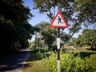 Triangular school ahead sign plate near the road. Drive slow sign