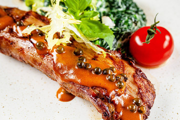 Wall Mural - Spanish cuisine. Veal steak with spinach and cream. Red wine is on the table. girl holding in hands a knife and a fork in a restaurant. background image, copy space text