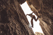 Rock climber in a canyon, pressing between two walls.