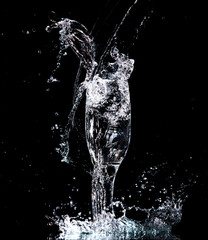 Wall Mural - Water with splashes in a glass on a black background