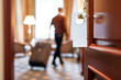 © Svitlana - Expecting comfortable stay. Cropped shot of middle-aged businessman in casual wear with suitcase entering his room in the background. A door with a sign at the front.