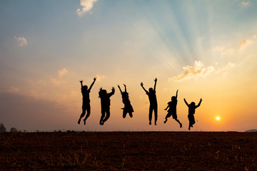 silhouette group of happy children jumping playing on mountain at sunset, summer time