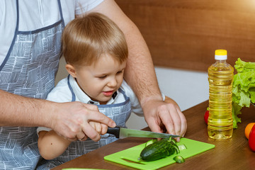 Front view father and son in kitchen cut vegetables for salad