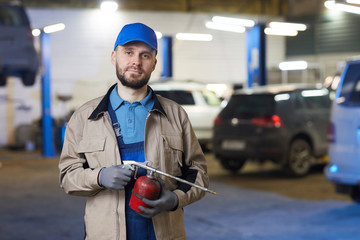 Horizontal waist up portrait of mature Caucasian auto mechanic holding gas torch looking at camera, copy space